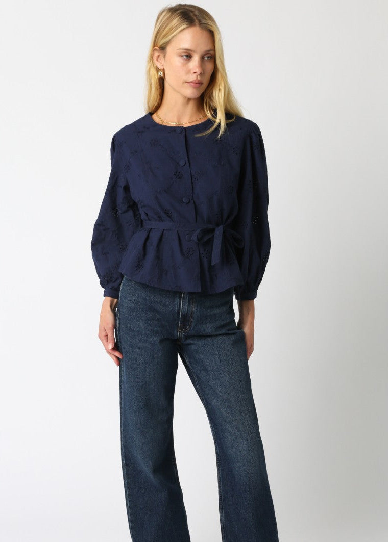 Woman wearing a navy blue top and jeans on a white background