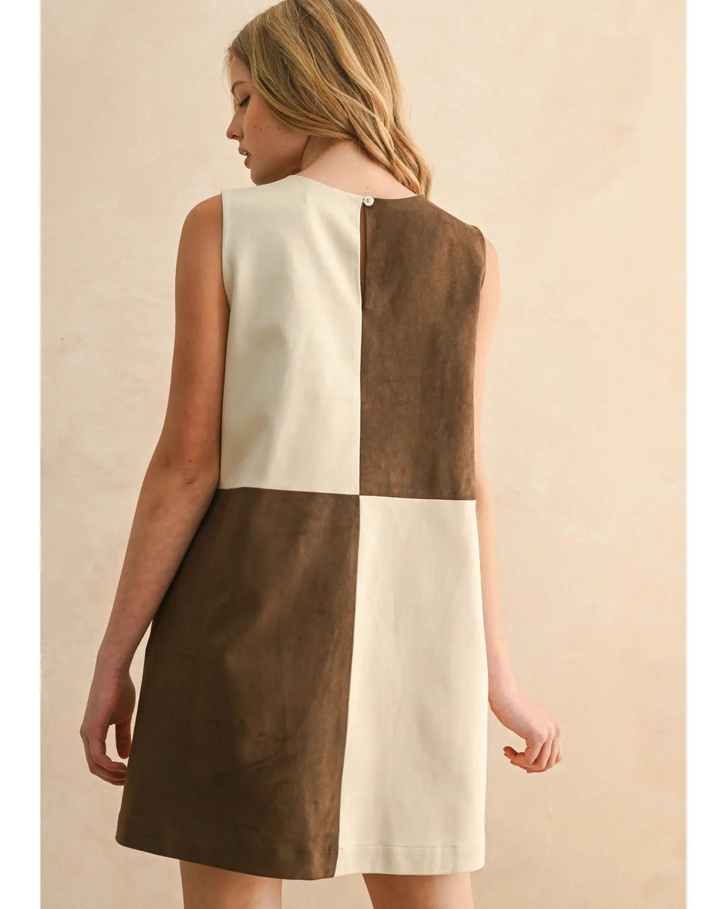 Woman wearing a two-tone dress with brown and white sections on a beige background