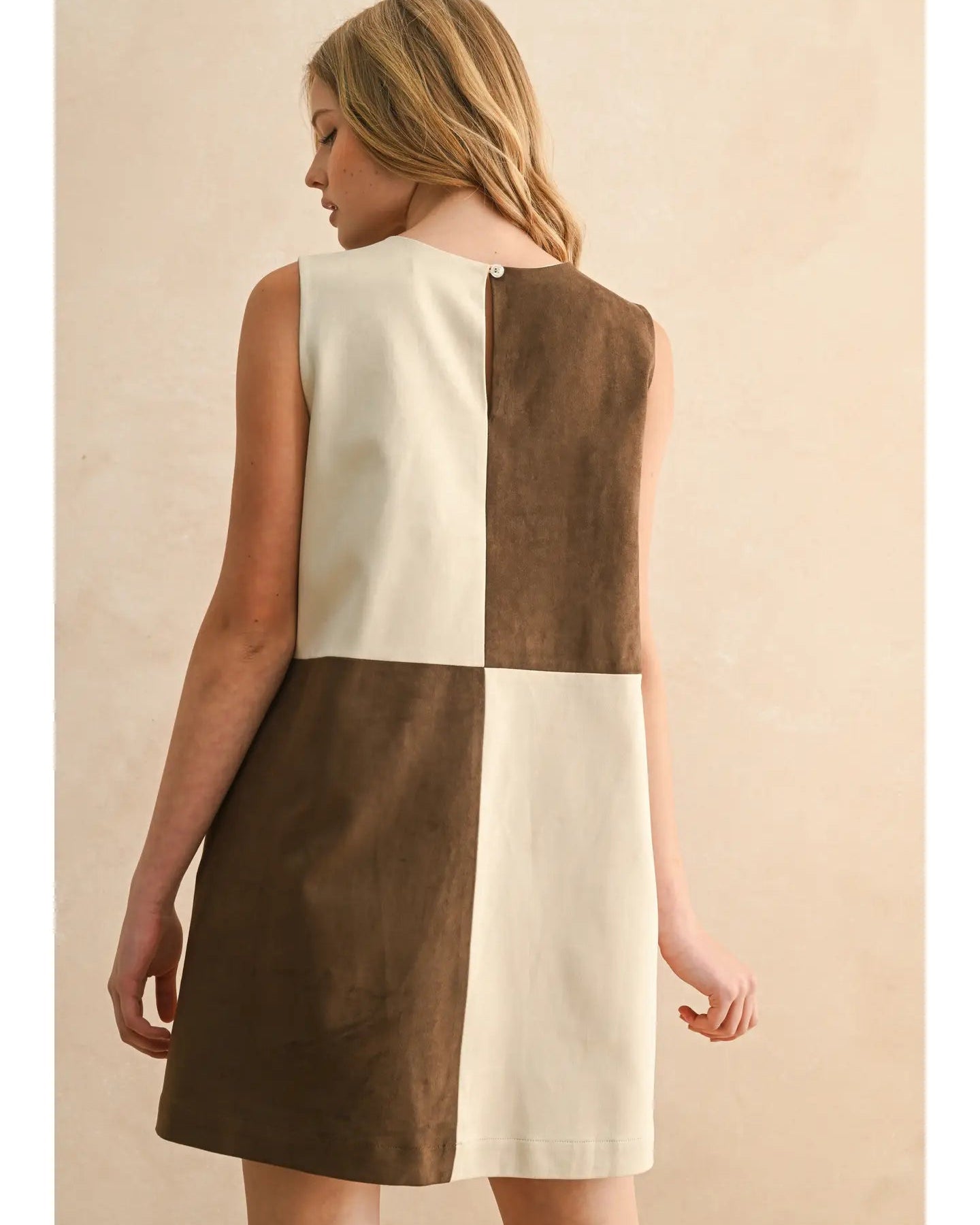 Woman wearing a two-tone dress with brown and white sections on a beige background