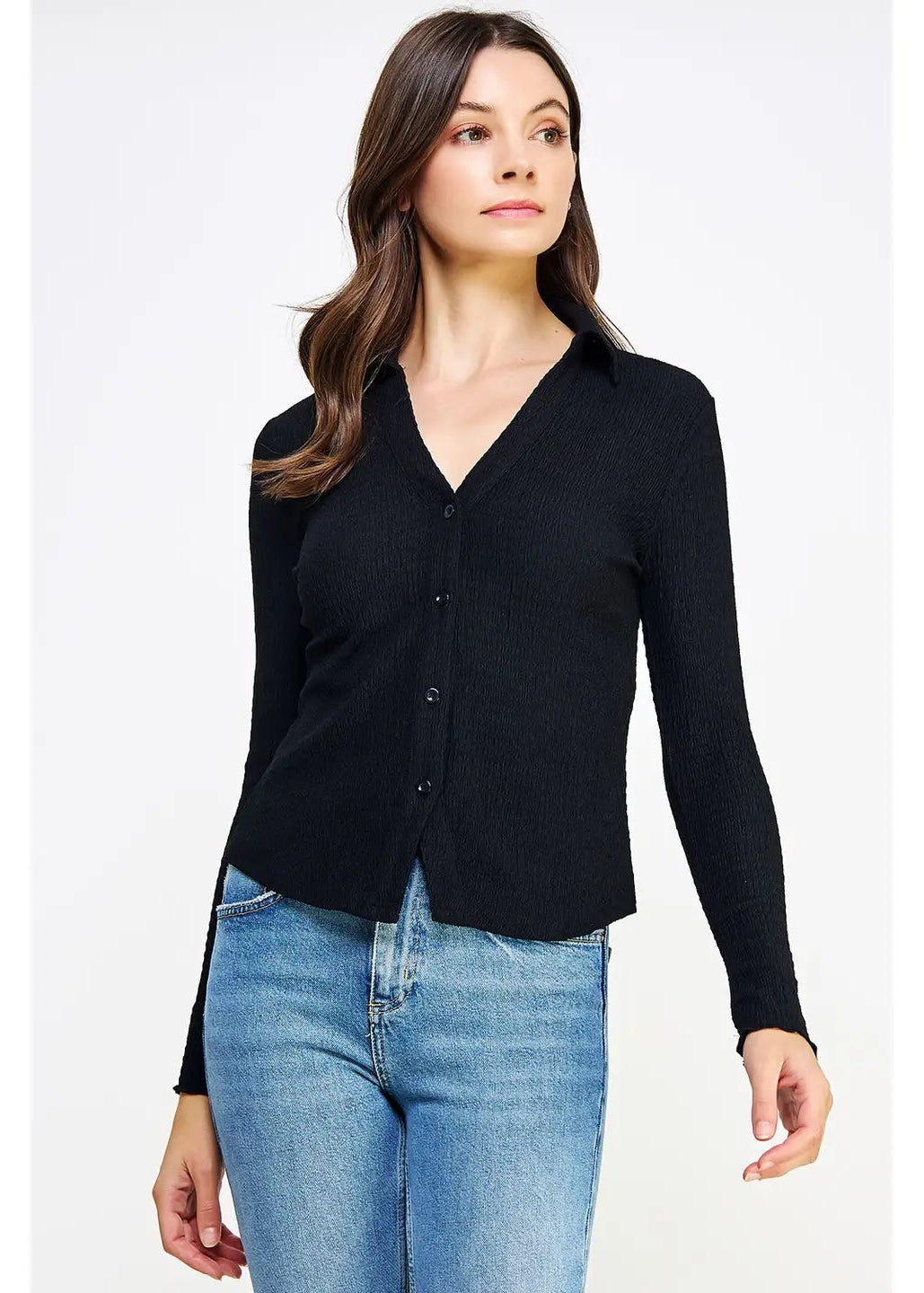 Woman wearing a black cardigan and blue jeans on a white background