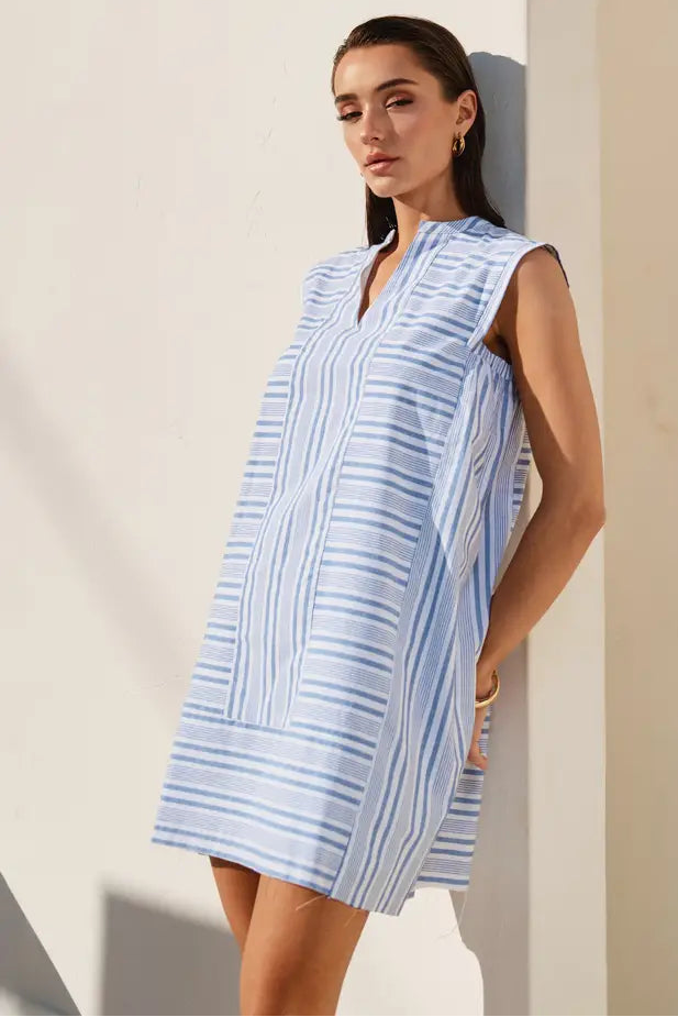 Woman wearing a blue and white striped dress against a neutral background